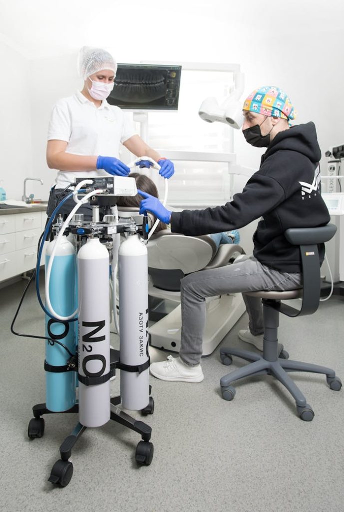 Dental professional assisting a patient with nitrous oxide in a clinic setting.
